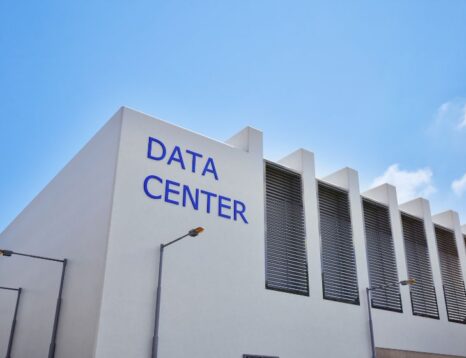 White data center building with a blue 'DATA CENTER' sign against a clear blue sky.