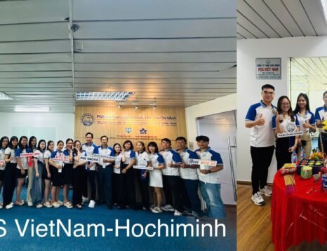 Group of staff in white and blue shirts posing for a team photo at PGS Vietnam Ho Chi Minh event, holding signs and thumbs up.
