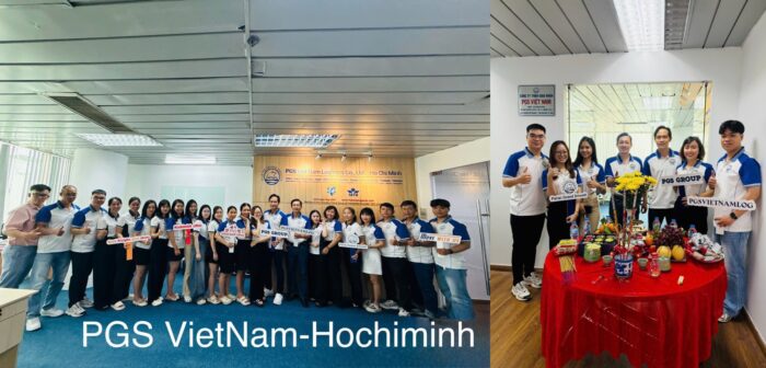 Group of staff in white and blue shirts posing for a team photo at PGS Vietnam Ho Chi Minh event, holding signs and thumbs up.